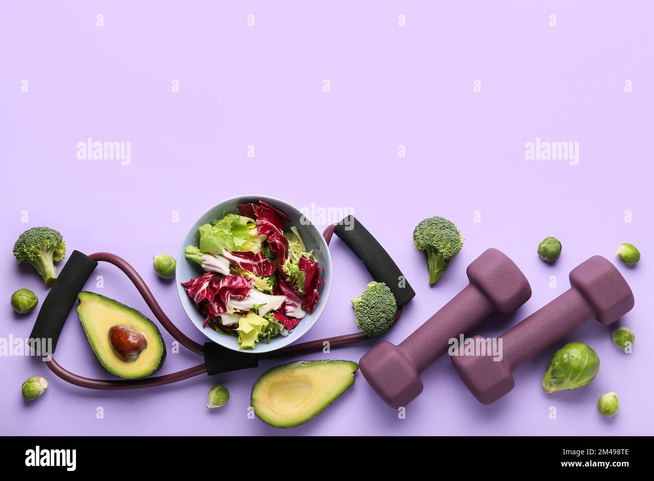 Schüssel mit Gemüsesalat, Kurzhanteln und Expander auf farbigem Hintergrund Stockfoto