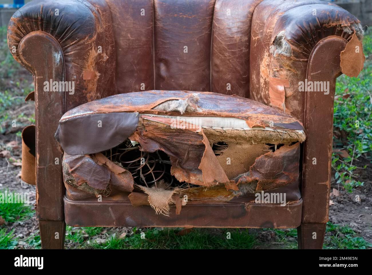 Defekter alter Ledersessel in einem Garten Stockfoto