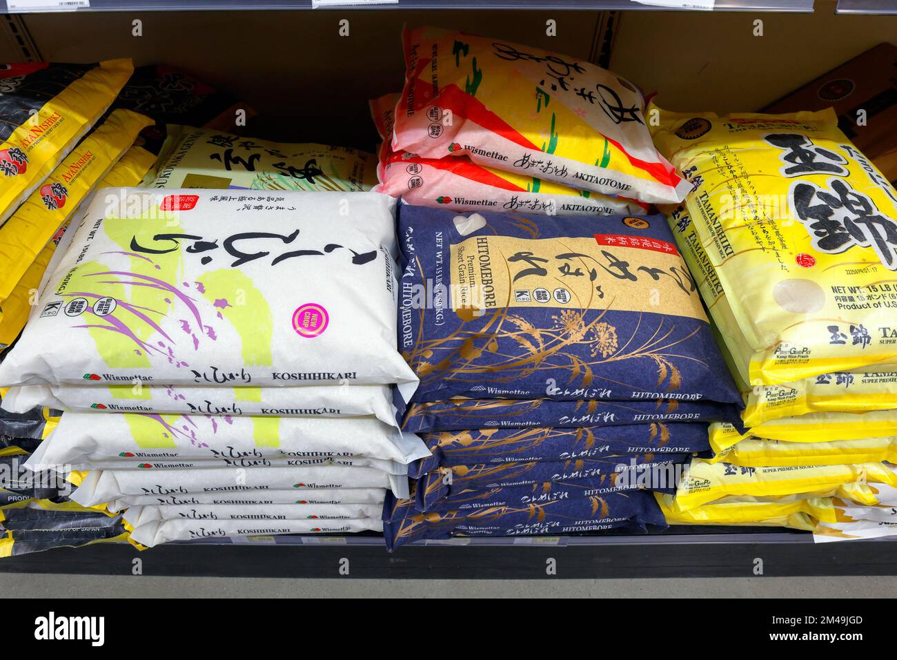Beutel mit japanischem Kurzkornreis auf einem Regal im Supermarkt. Die Marken verwenden Variationen des Koshihikari-Kultivars von Oryza sativa Japonica. Stockfoto