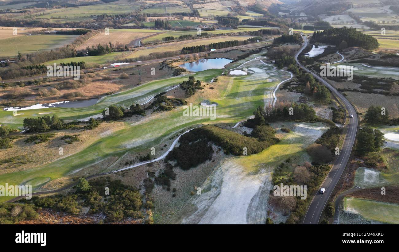 Ein Blick aus der Vogelperspektive auf einen Gleneagles Golfplatz entlang der Landstraße an einem sonnigen Tag mit Feldern und Hügeln im Hintergrund Stockfoto