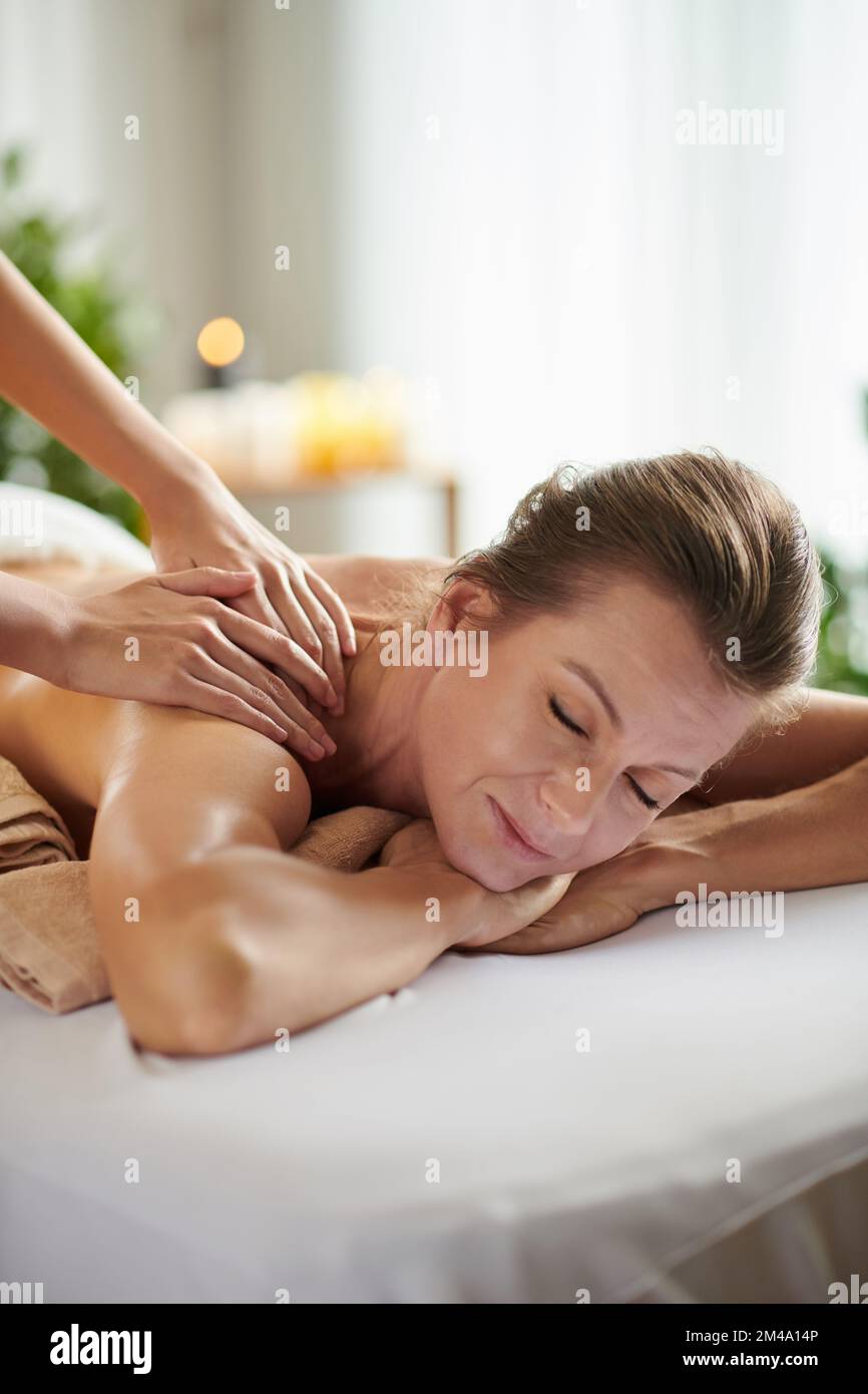 Reife Frau genießt Schultermassage im Salon, um Stress und Angst zu beseitigen Stockfoto