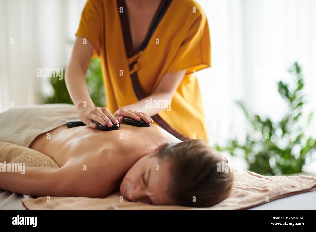 Entspannende Rückenmassage mit heißen Basaltsteinen Stockfoto