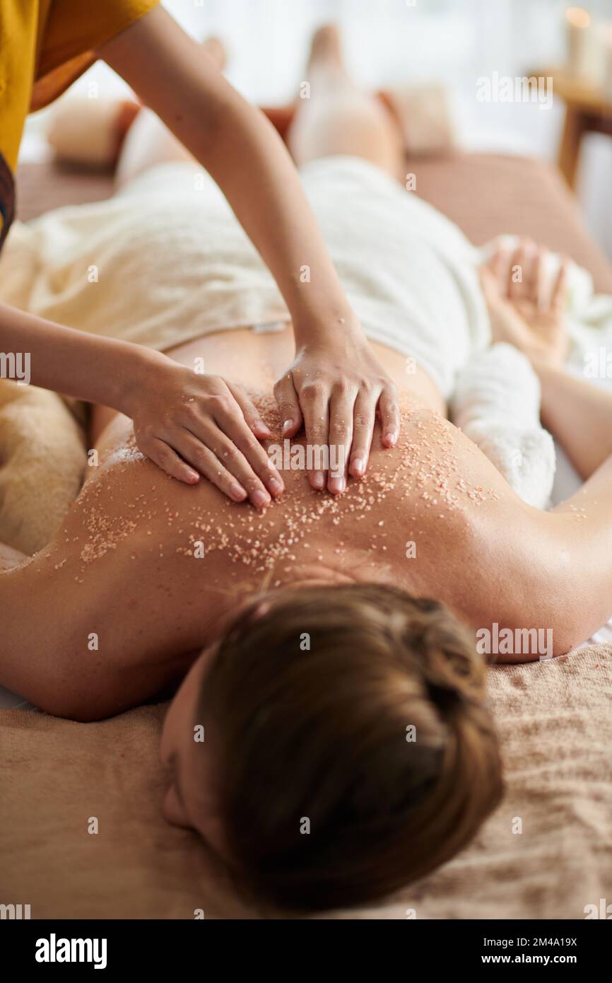 Eine Frau, die eine luxuriöse Spa-Behandlung mit warmem Saatöl und Meersalz-Peeling erhält Stockfoto