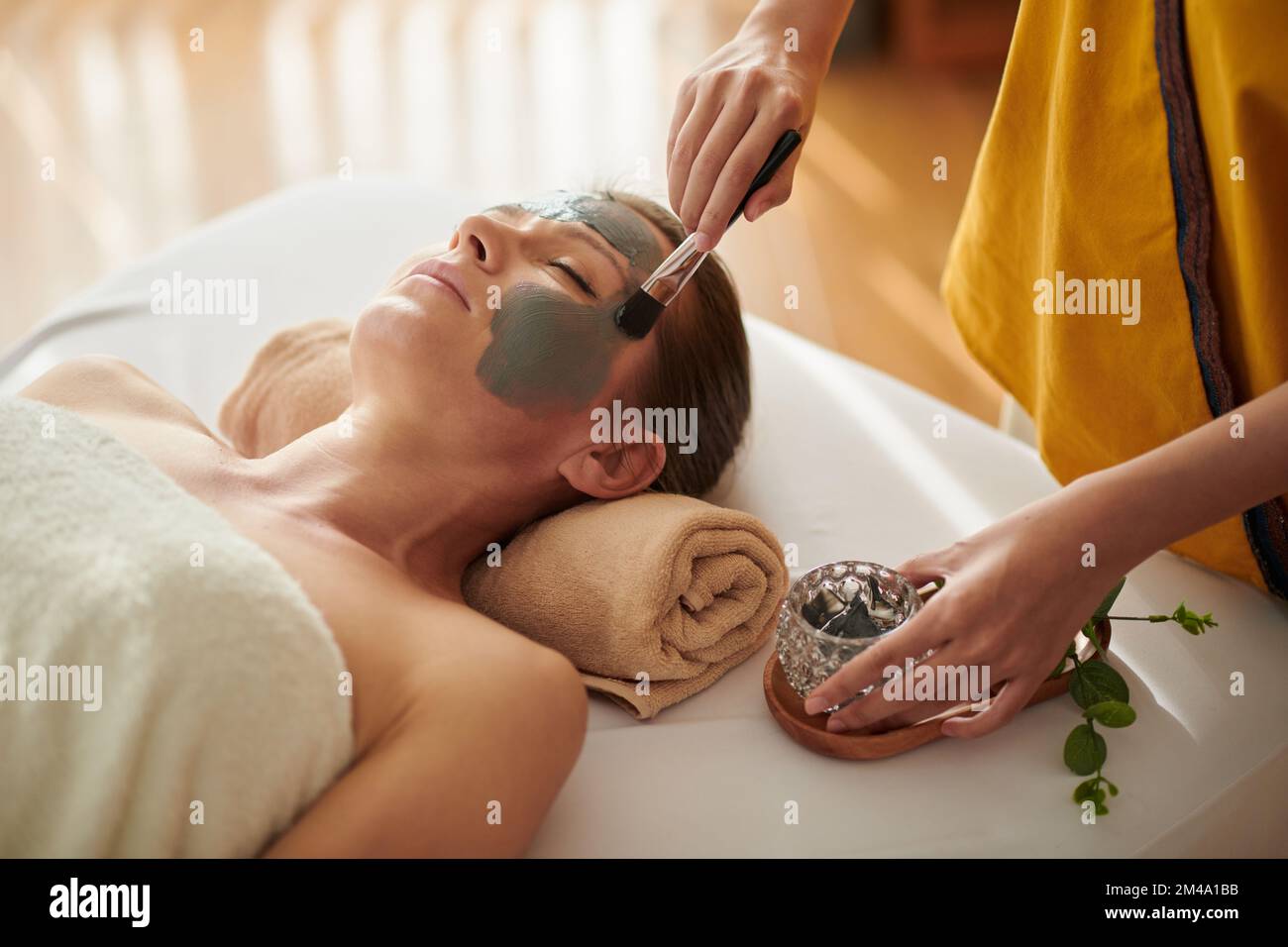 Nahaufnahme einer Frau mittleren Alters, die Meeremineralien-Schlammmasken im Kursalon bekommt Stockfoto