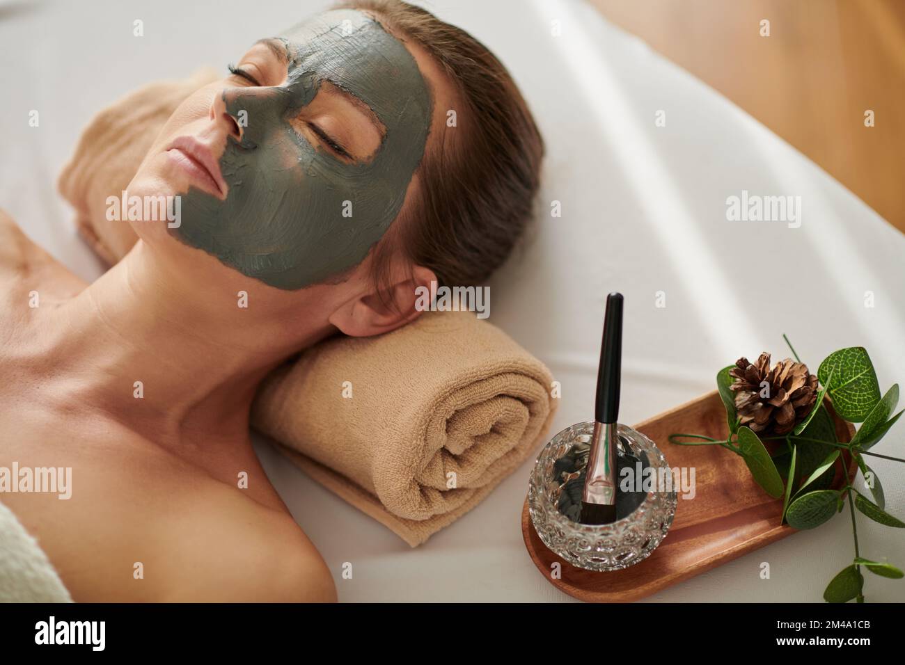 Entspannte Frau mit Tonmaske auf der Hälfte ihres Gesichts Stockfoto