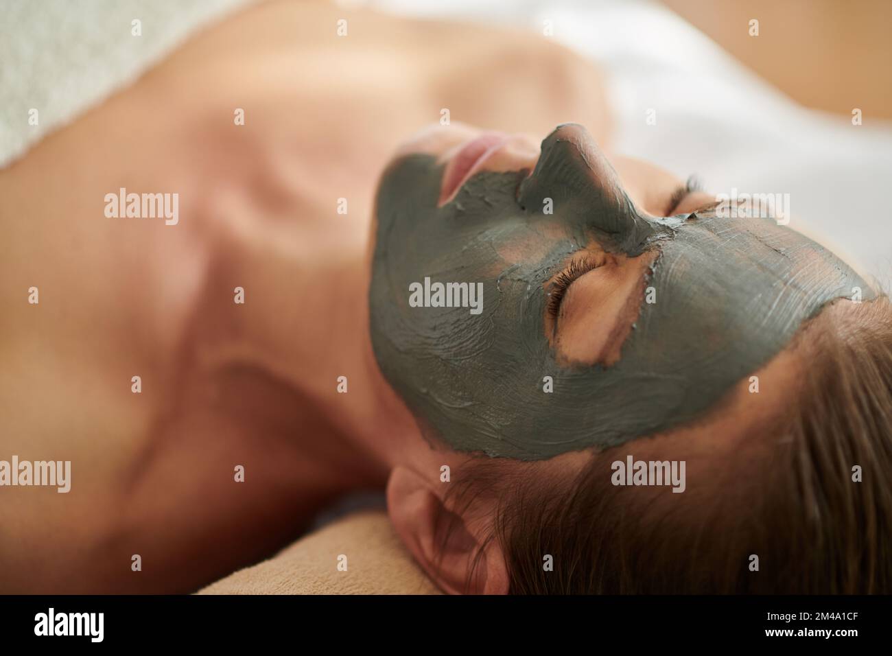 Gäste im Wellnessbereich entspannen sich mit einer verjüngenden und entgiftenden Tonmaske im Gesicht Stockfoto