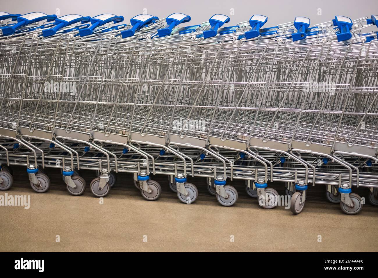 Eine Reihe gestapelter Supermarkt-Trolleys. Eine Reihe gestapelter Metallwagen für Supermärkte ist in der Perspektive zu sehen. Große Gruppe von Einkaufswagen in r Stockfoto