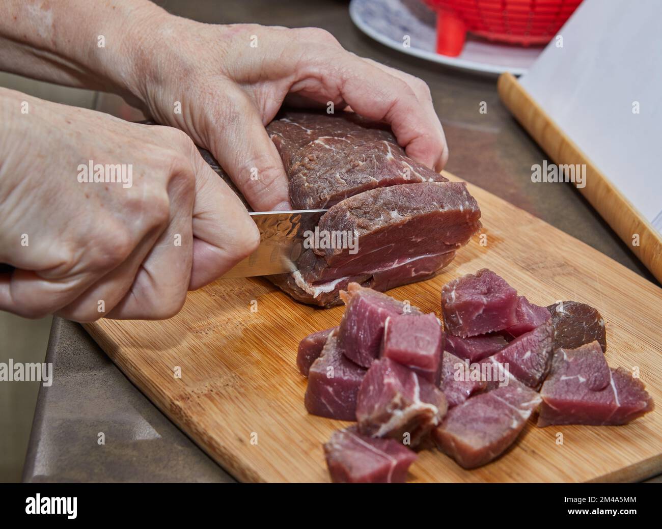Der Küchenchef schneidet das Rindfleisch zum Kochen in Würfel Stockfoto