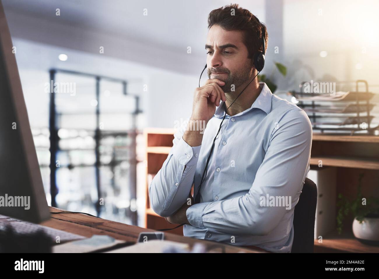 Hmmm... Lass mich darüber nachdenken. Ein junger Callcenter-Agent, der spät in einem Büro arbeitet. Stockfoto