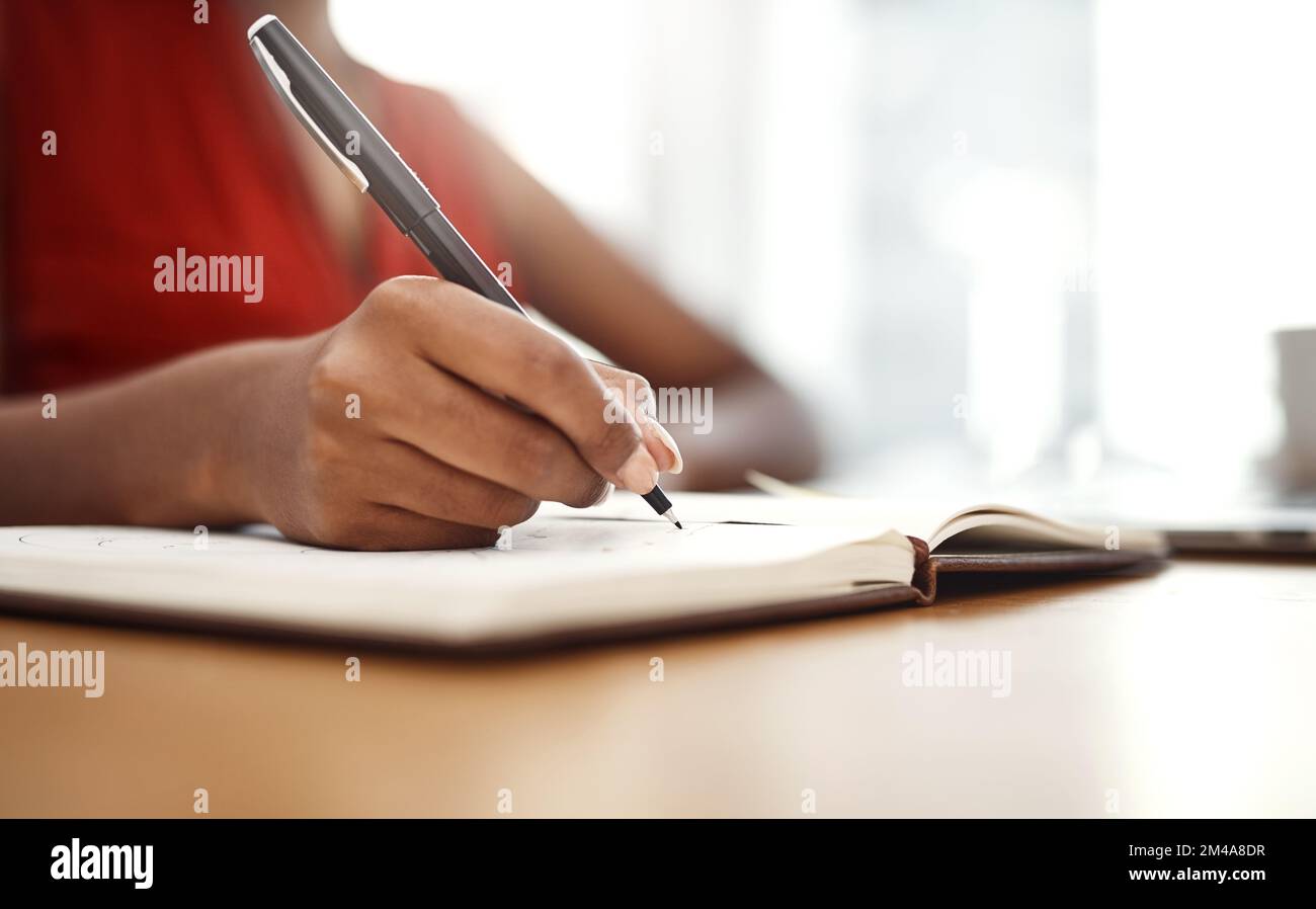 Dinge zu Hause erledigen. Eine unbekannte Geschäftsfrau, die sich Notizen in ihr Notizbuch in ihrem Heimbüro schreibt. Stockfoto