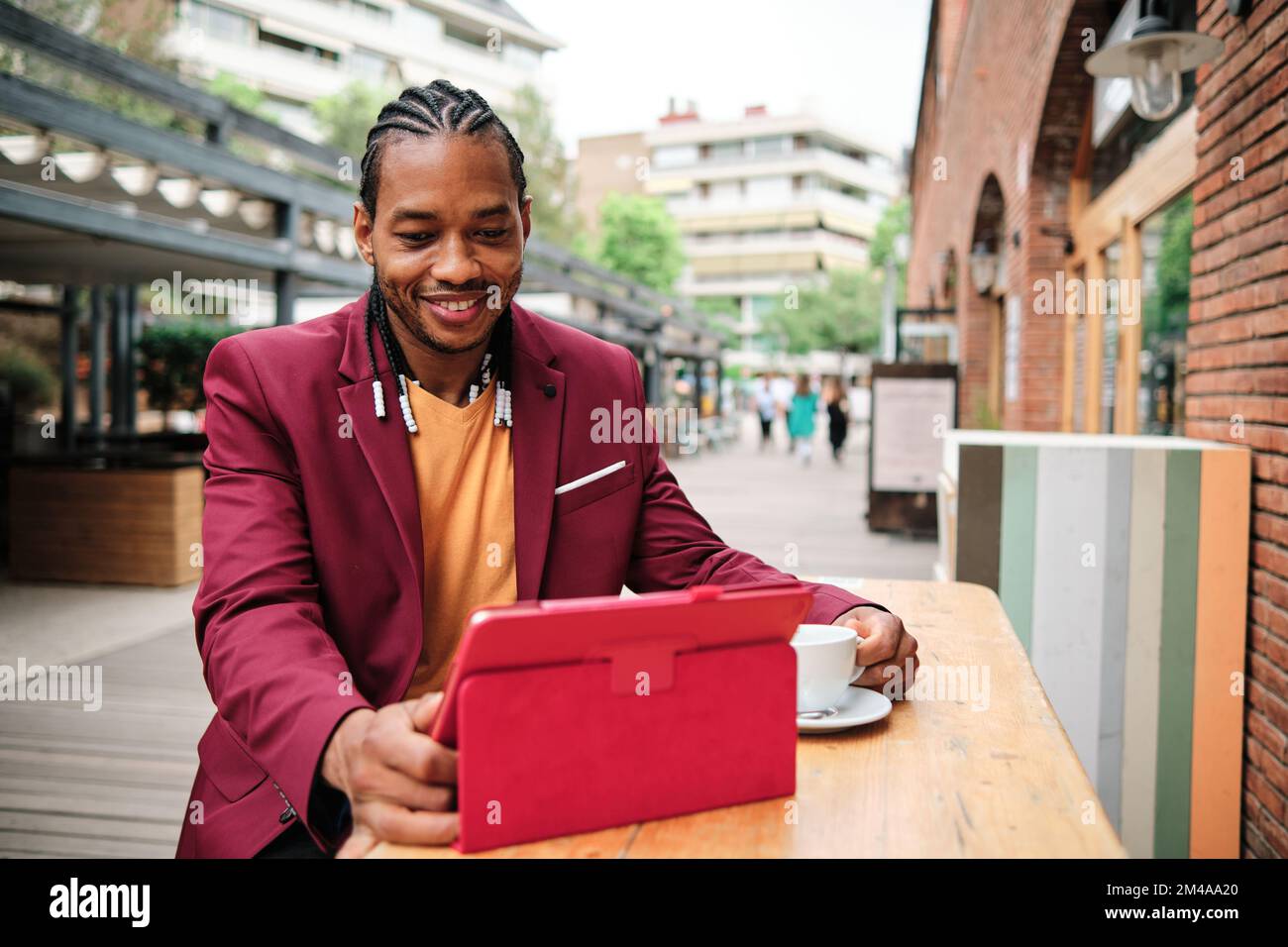 Eleganter afrikanischer Mann, der ein Tablet in einer Cafeteria benutzt Stockfoto