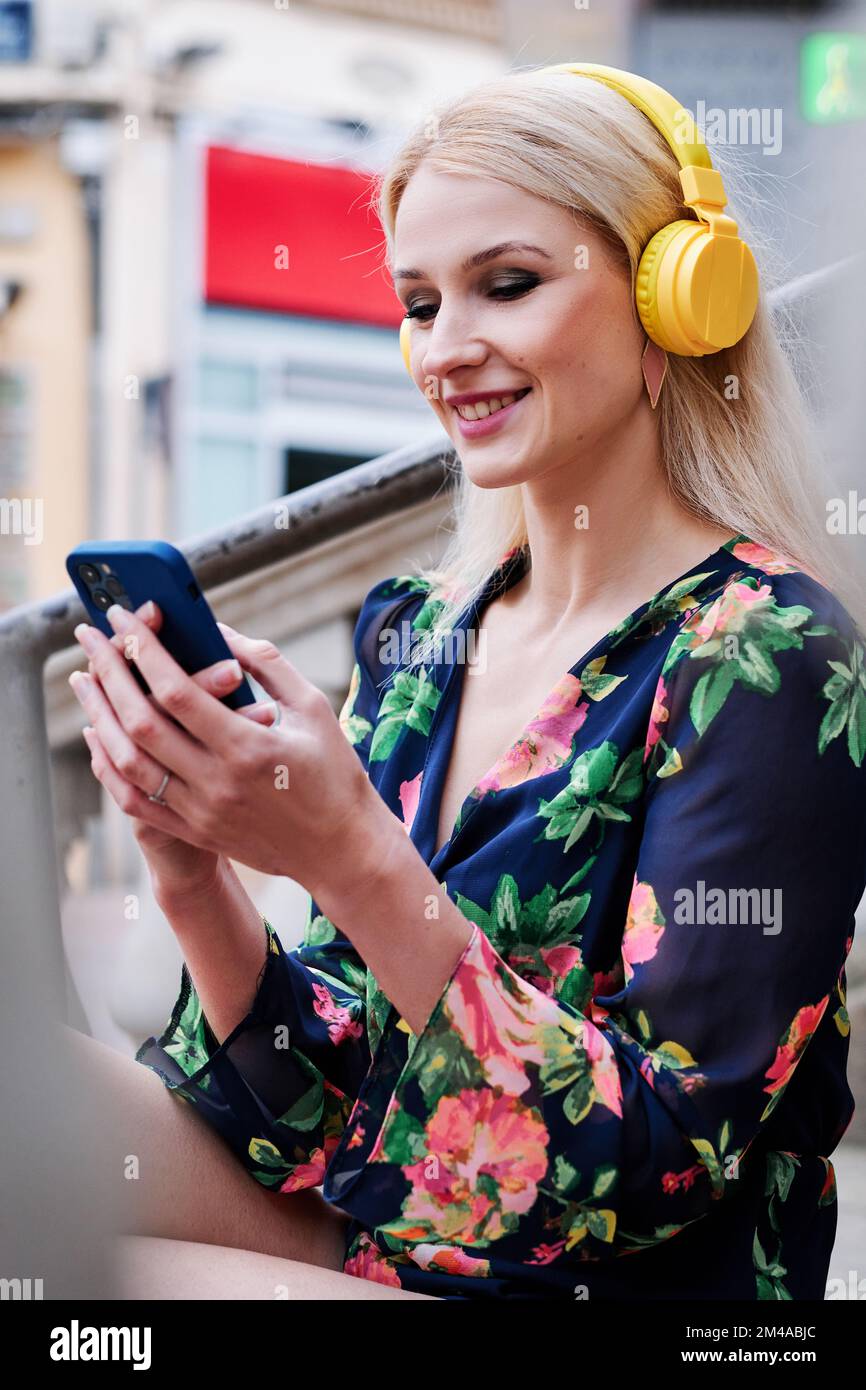 Blonde Frau, die Musik mit einem Handy hört Stockfoto