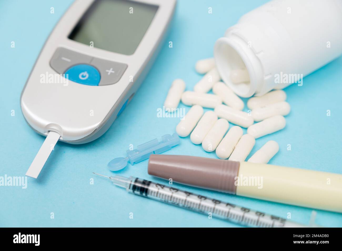 Glaukometer und Insulinspritze, Lanzengerät-Teststreifen. Auf blauem Hintergrund. Stockfoto