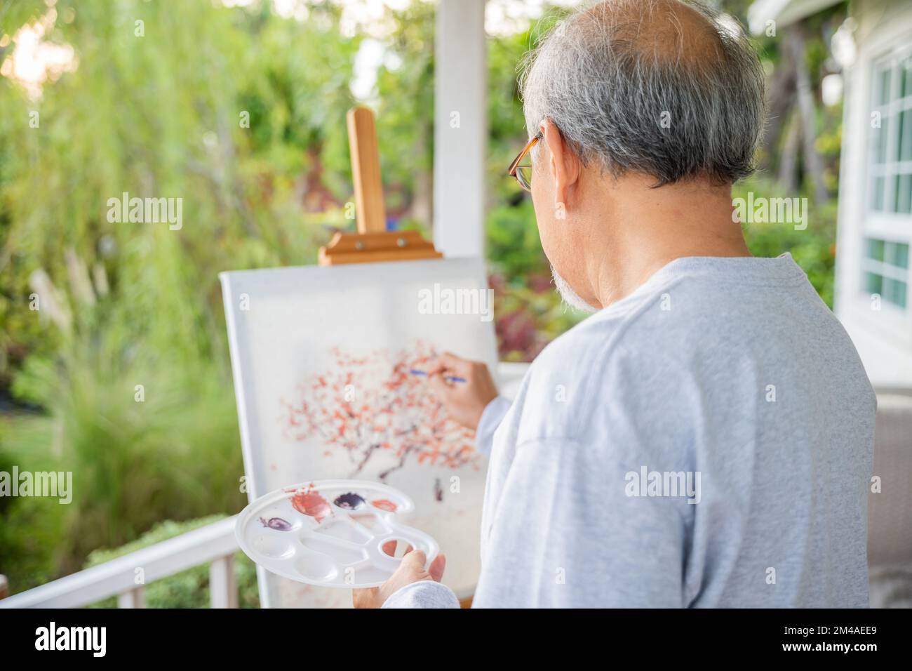 Lifestyle asiatischer älterer Mann, der Bilder mit Pinsel- und Ölfarben auf Leinwand malt Stockfoto