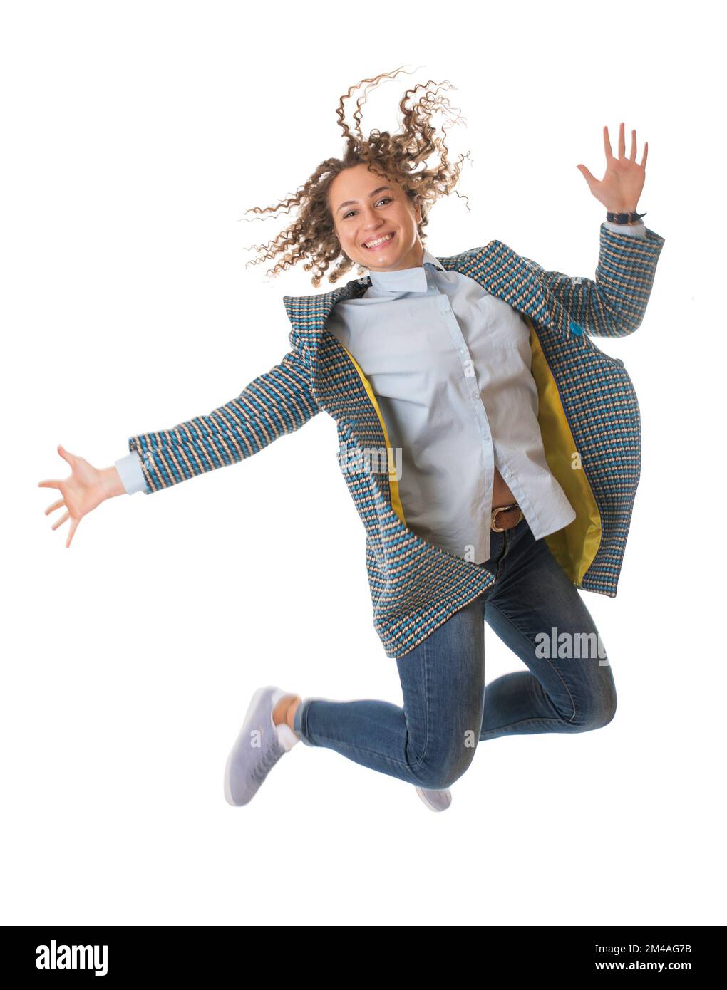 Hübsches junges Mädchen in einem hellen Mantel, das auf weißen Hintergrund springt Stockfoto
