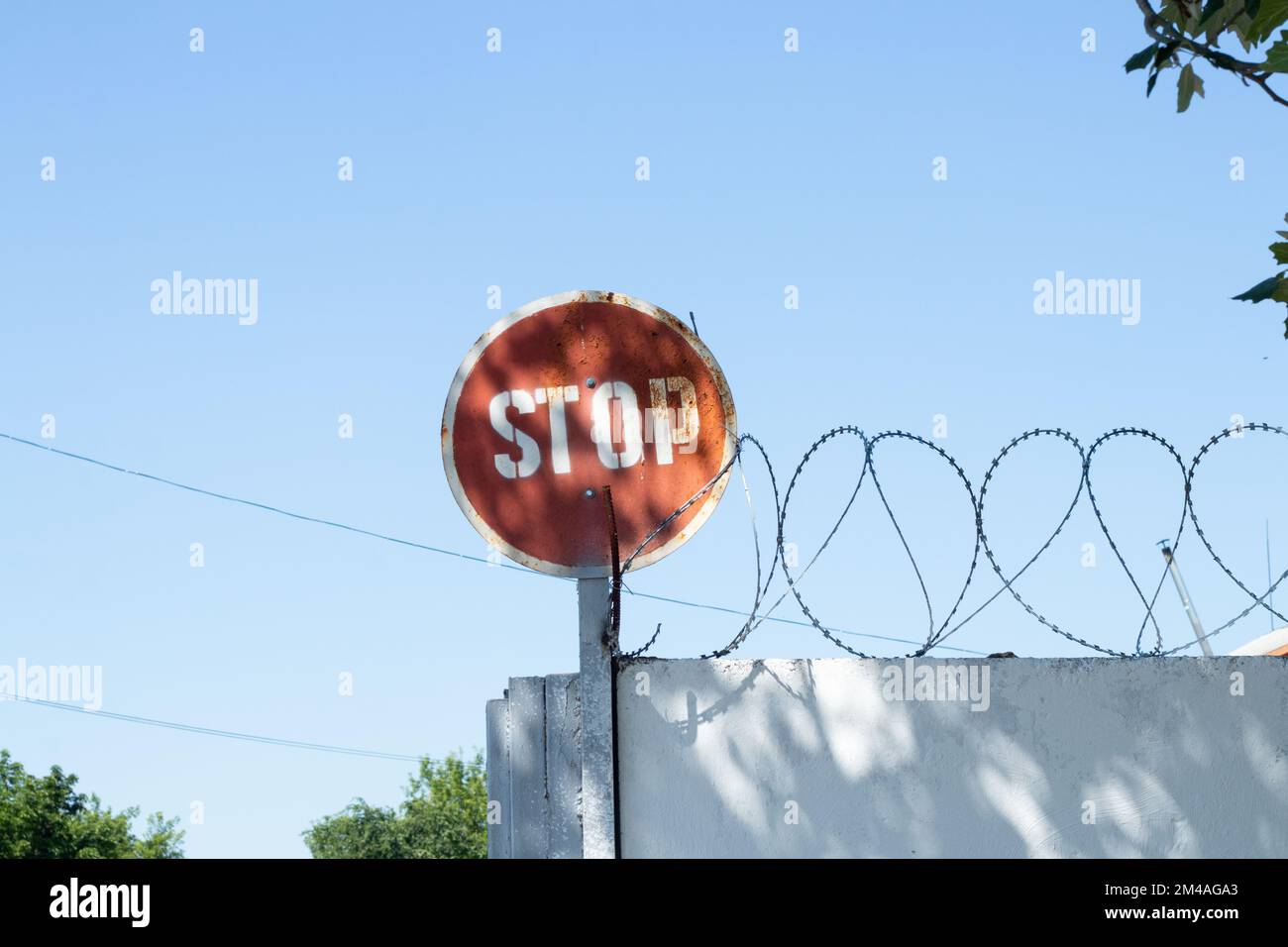 Stoppschild und Stacheldraht am Zaun gegen Stockfoto
