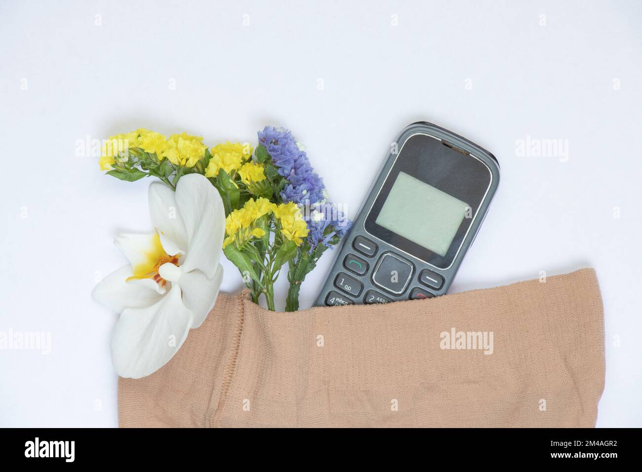 Telefon mit Drucktaste und blühende Blumen in Strumpfhosen auf einem isolierten Hintergrund Stockfoto