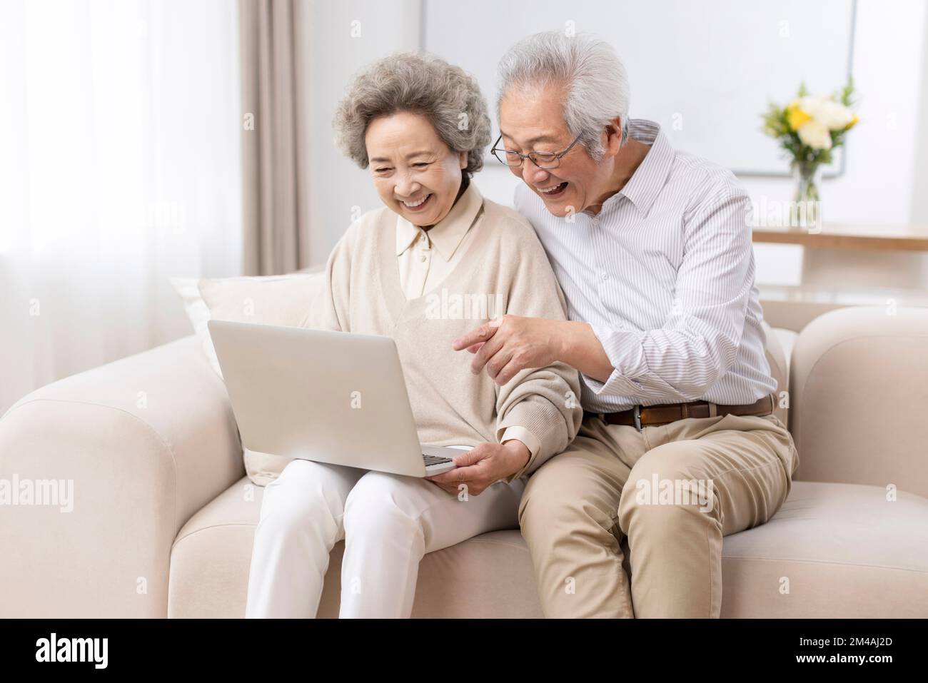 Fröhliches chinesisches Seniorenpaar, das zu Hause ein Laptop benutzt Stockfoto