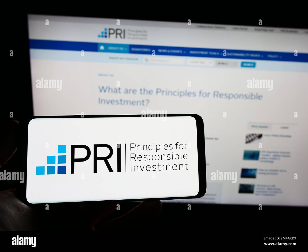 Person, die ein Smartphone mit dem Logo der UN Principles for Responsible Investment (PRI) auf dem Bildschirm vor der Website hält. Konzentrieren Sie sich auf das Display des Telefons. Stockfoto