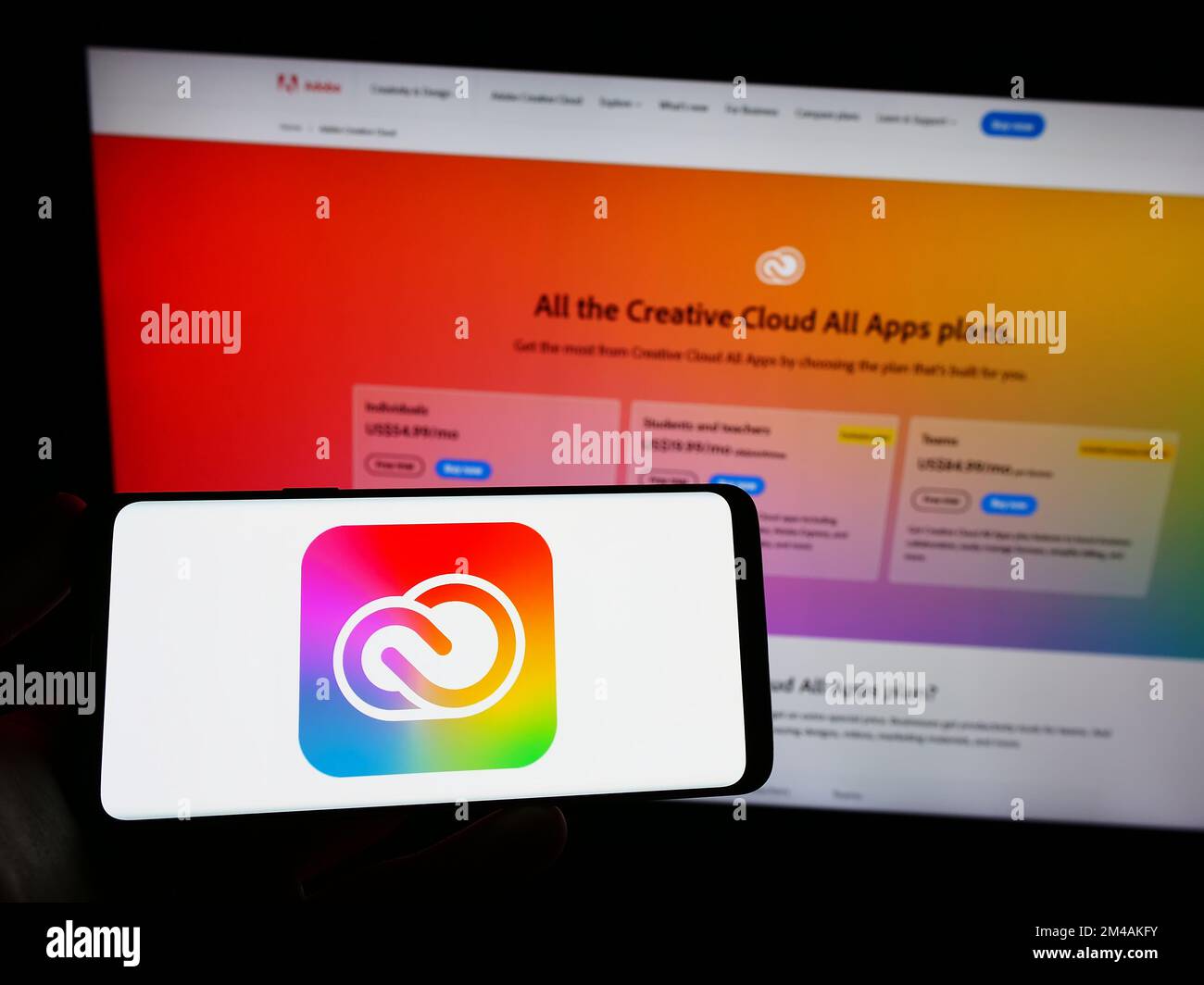 Person, die ein Mobiltelefon mit dem Logo der Software Adobe Creative Cloud auf dem Bildschirm vor der Unternehmenswebseite hält. Konzentrieren Sie sich auf das Display des Telefons. Stockfoto
