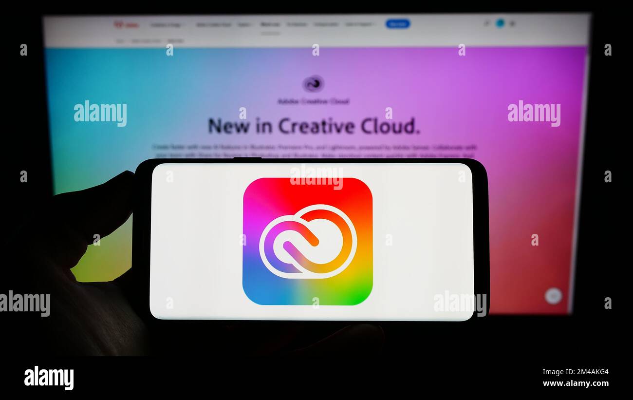 Person, die ein Mobiltelefon mit dem Logo der Software Adobe Creative Cloud auf dem Bildschirm vor der Unternehmenswebseite hält. Konzentrieren Sie sich auf das Display des Telefons. Stockfoto