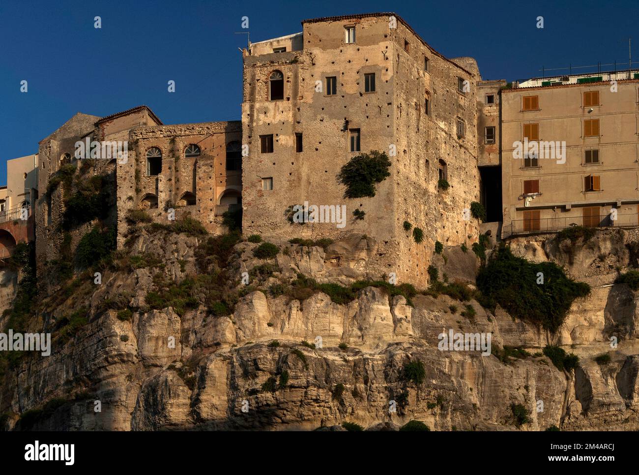 Aus dem hügeligen Gipfel der Sandsteinklippen, die die historische Altstadt von Tropea an der Costa degli Dei (Küste der Götter) im Westen Kalabriens, Süditalien, stützen, scheinen ältere Steinbauten zu wachsen. Stockfoto