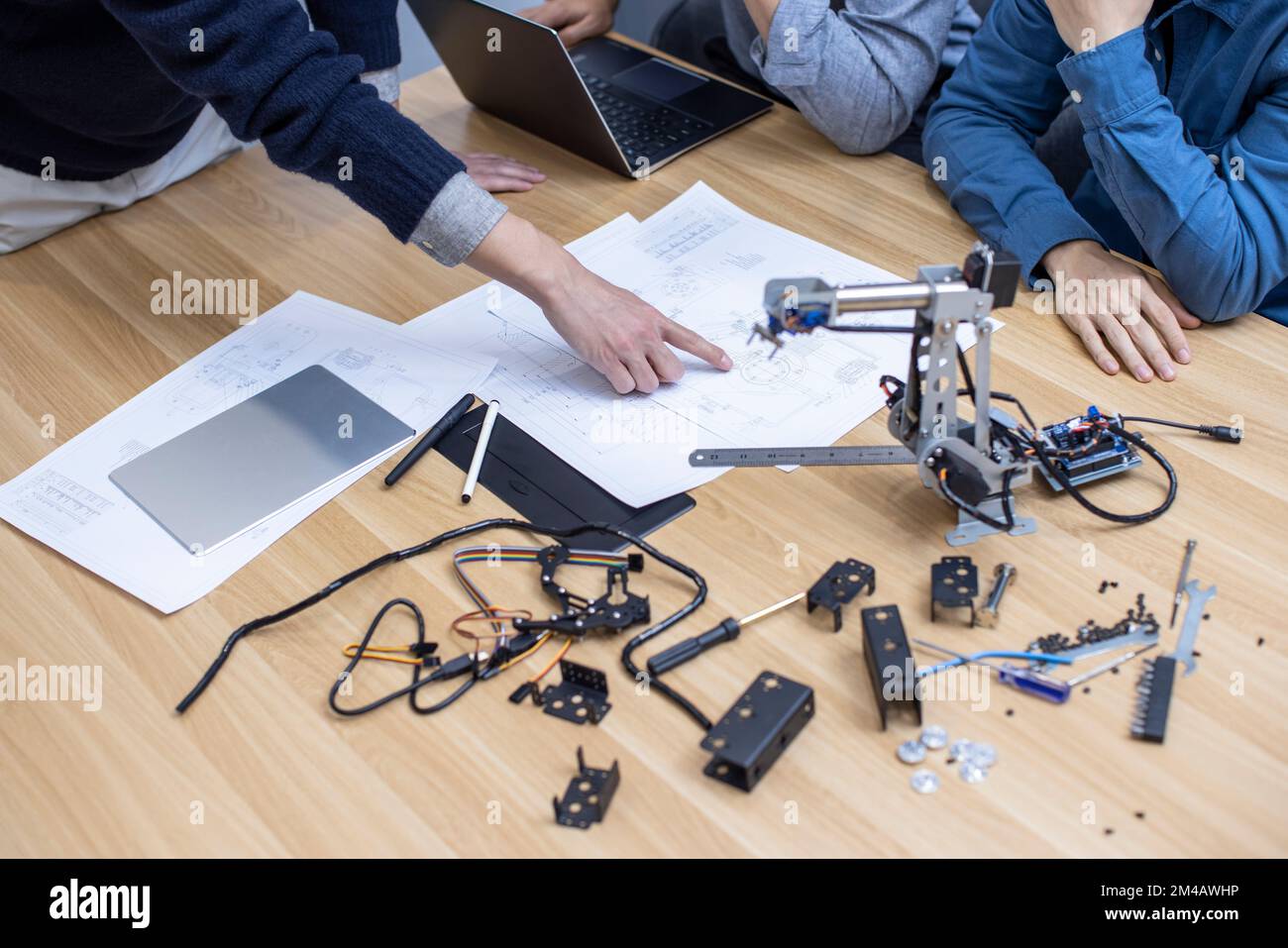 Selbstbewusste chinesische Konstrukteure überprüfen einen Roboterarm Stockfoto