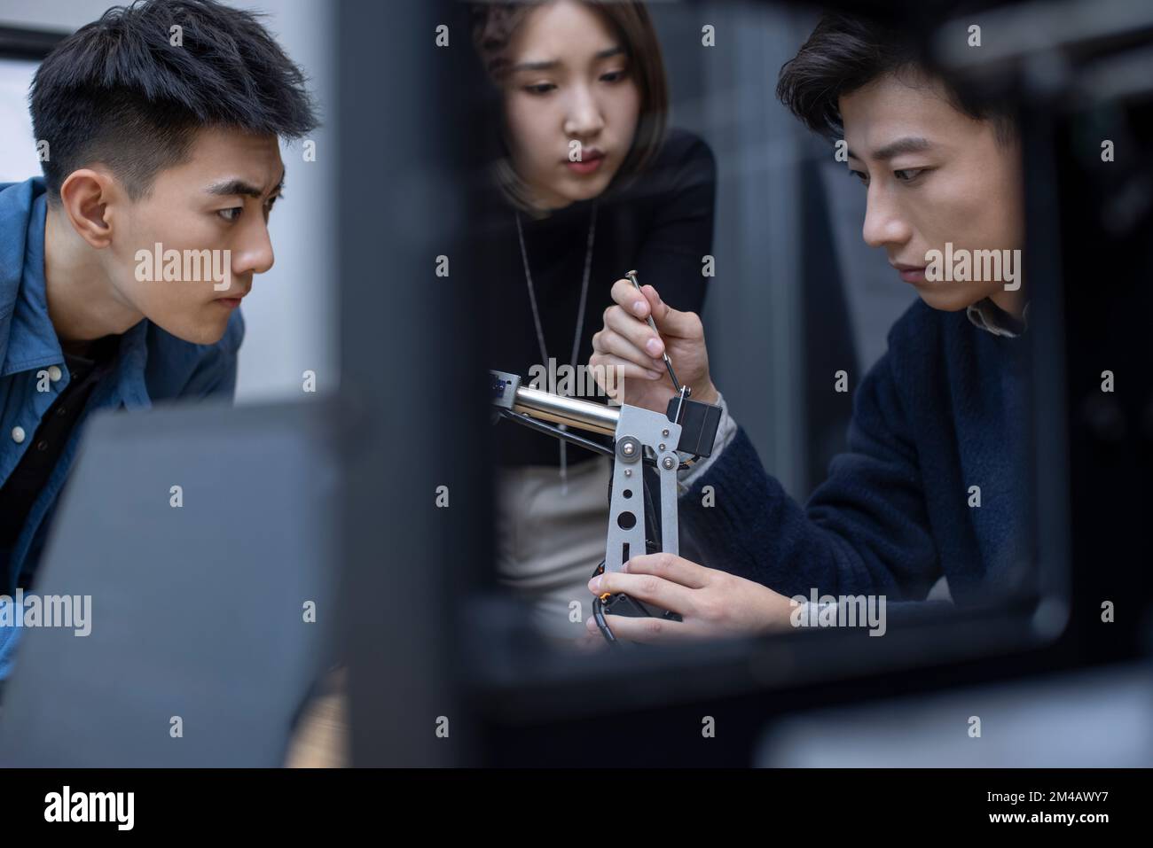 Selbstbewusste chinesische Konstrukteure überprüfen einen Roboterarm Stockfoto