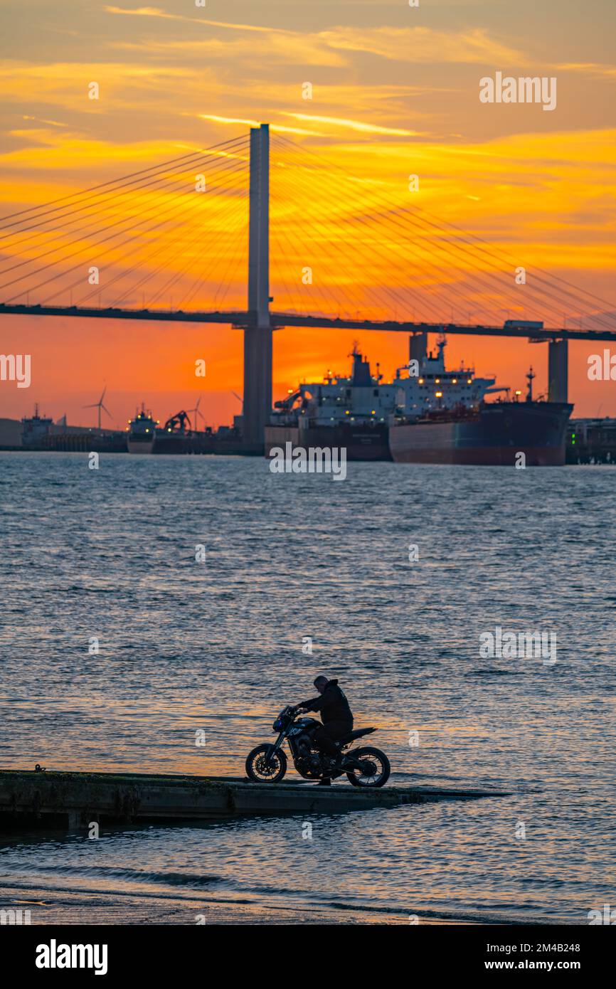 Die Dartford Bridge über die Themse bei Sonnenuntergang mit Motorradfahrern auf dem Anleger in der Nähe des Wassers Stockfoto