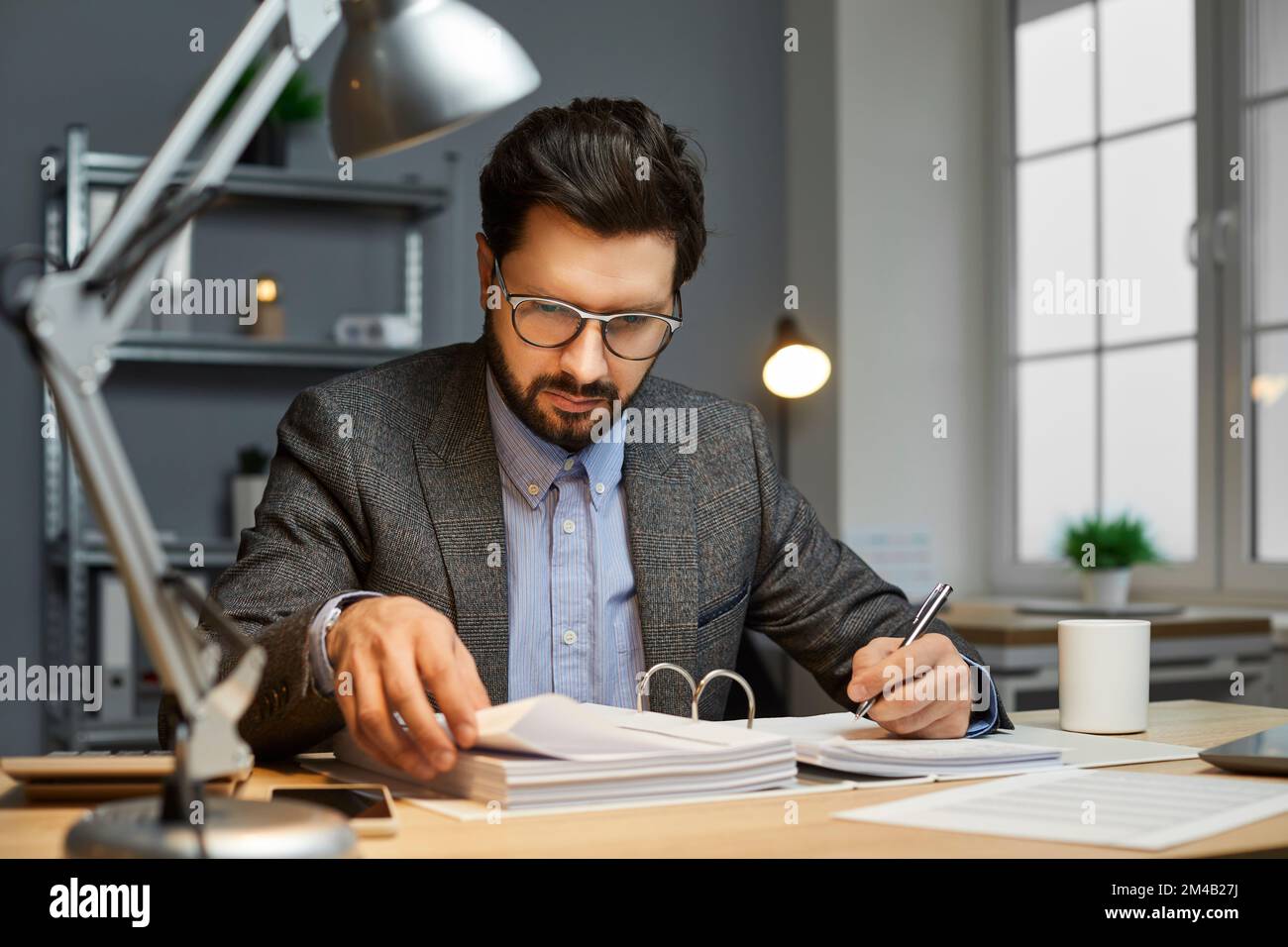 Männlicher Buchhalter, der an einem Schreibtisch sitzt, Papierkram erledigt und Dokumente liest Stockfoto