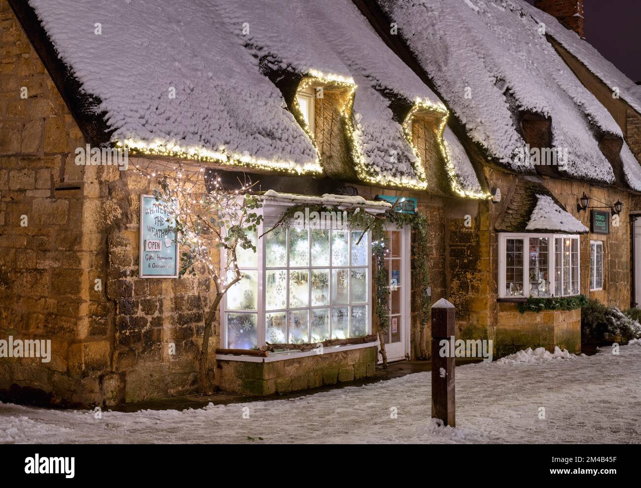 Was auch immer das Wetter Geschenkeshop im Schnee bei Nacht. Broadway, Cotswolds, Worcestershire, England Stockfoto
