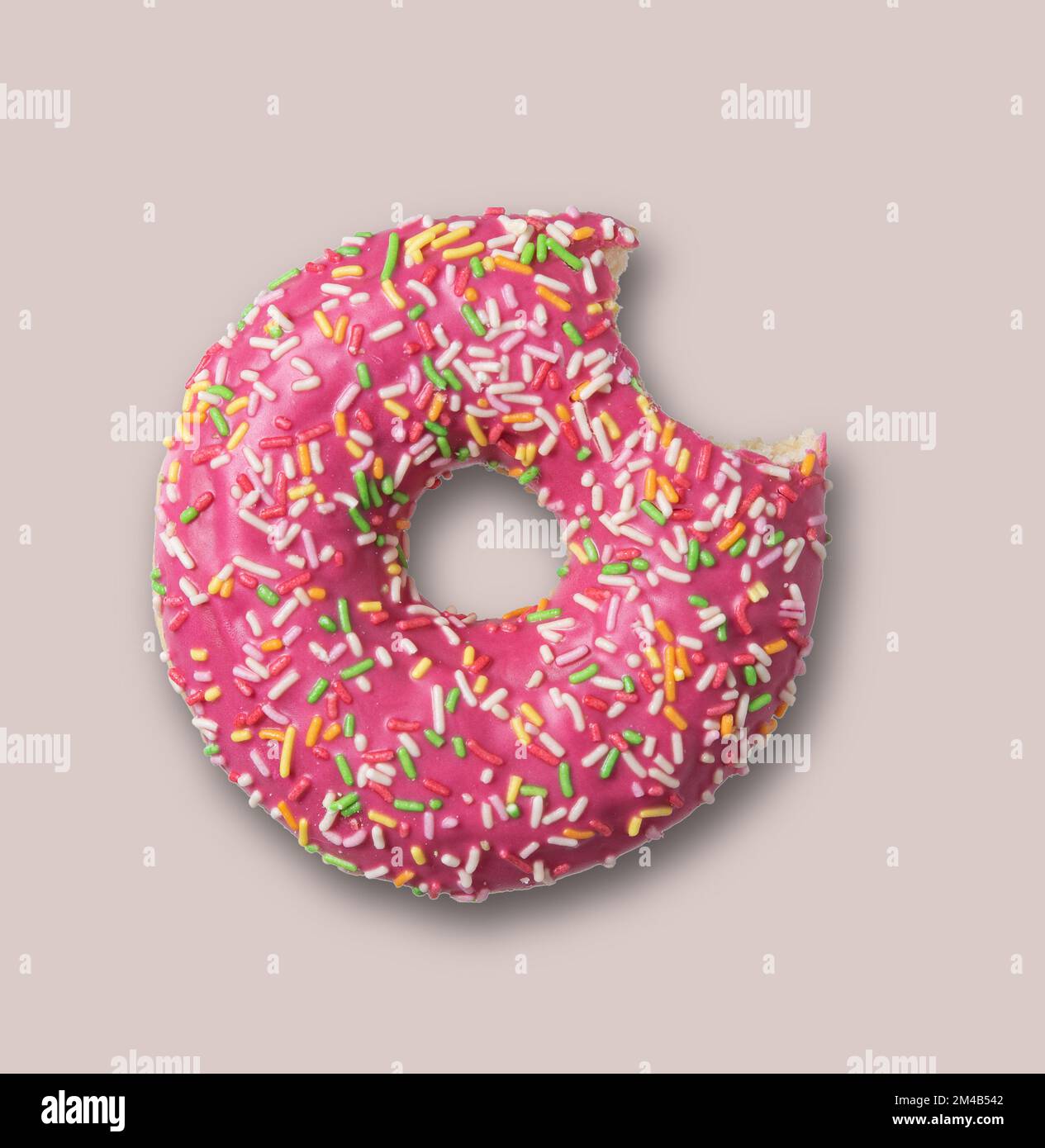 Köstlicher glasierter, rosafarbener BissDonut mit Streuseln auf grauem Hintergrund. Draufsicht. Konzept-Food Stockfoto