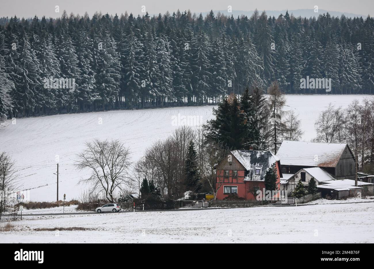 Markneukirchen, Deutschland. 20.. Dezember 2022. Ein Auto fährt an einem schneebedeckten Bauernhof in der Region Vogtland vorbei. Selbst in den höheren Regionen werden die Temperaturen in den nächsten Tagen auf die positiven Grad ansteigen. Mild, bewölkt und regnerisch - das sind die Wetteraussichten für die Tage vor Weihnachten in Deutschland. Kredit: Jan Woitas/dpa/Alamy Live News Stockfoto