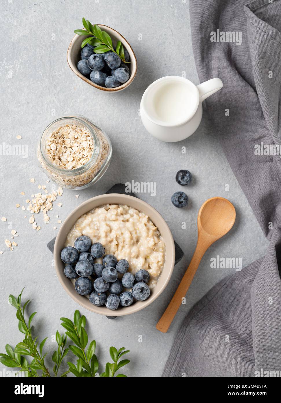 Haferbrei mit Blaubeeren in der Schüssel auf blauem Hintergrund mit Beeren und Milch. Das Konzept eines leckeren, nahrhaften und gesunden Frühstücks. Bis Stockfoto