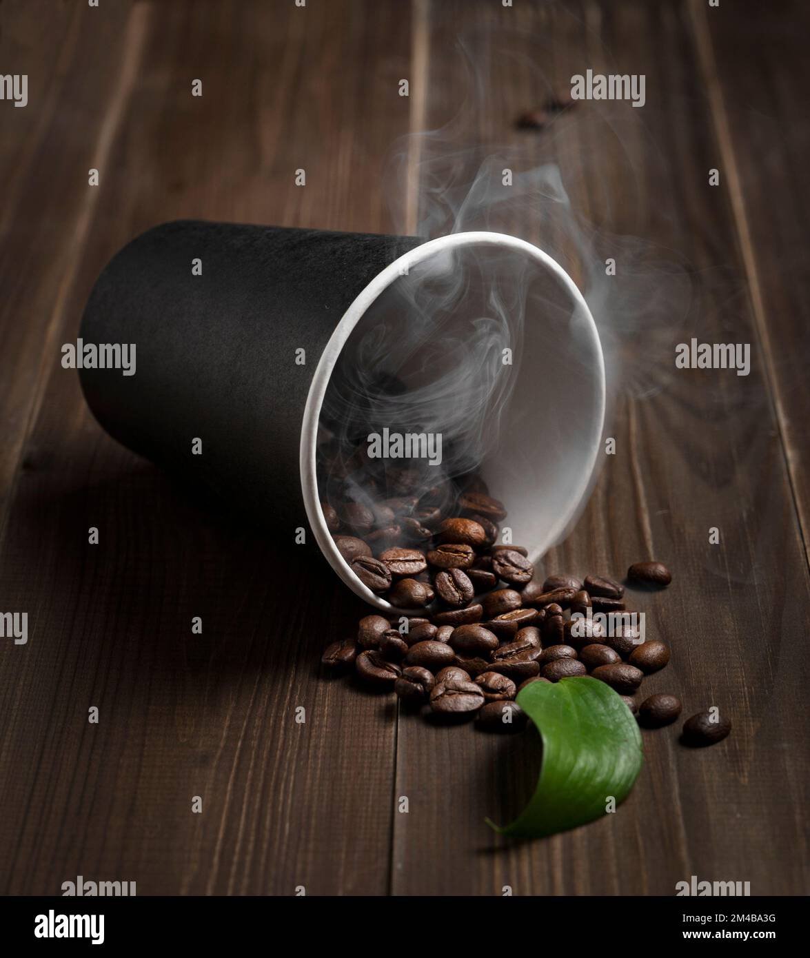 Frische aromatische Kaffeebohnen auf dunklem Holzhintergrund aus einer Nahaufnahme eines Einwegbechers aus Kunststoff. Das Konzept eines Morgenenergietrinks. Stockfoto