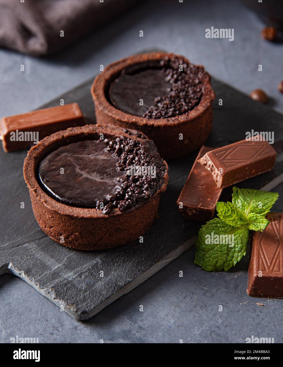Mini-Schokoladentörtchen mit Schokoladenstückchen auf dunklem Hintergrund. Makroansicht Stockfoto