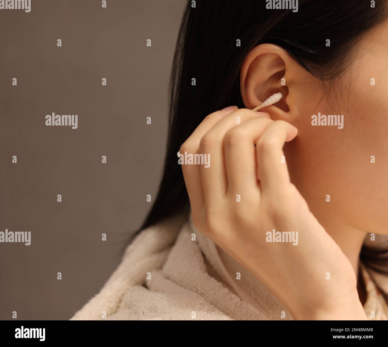 Eine Frau reinigt ihr Ohr nach dem Duschen mit einem Wattestäbchen und pflückt das Ohr mit Wattestäbchen von Hand Stockfoto