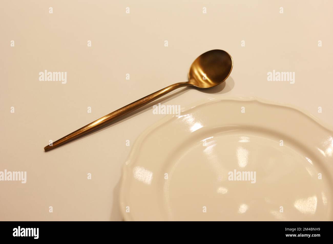 Ein Set koreanischer Messinglöffel mit leerem weißem Gericht auf dem Tisch, der Löffel auf dem Gericht Stockfoto