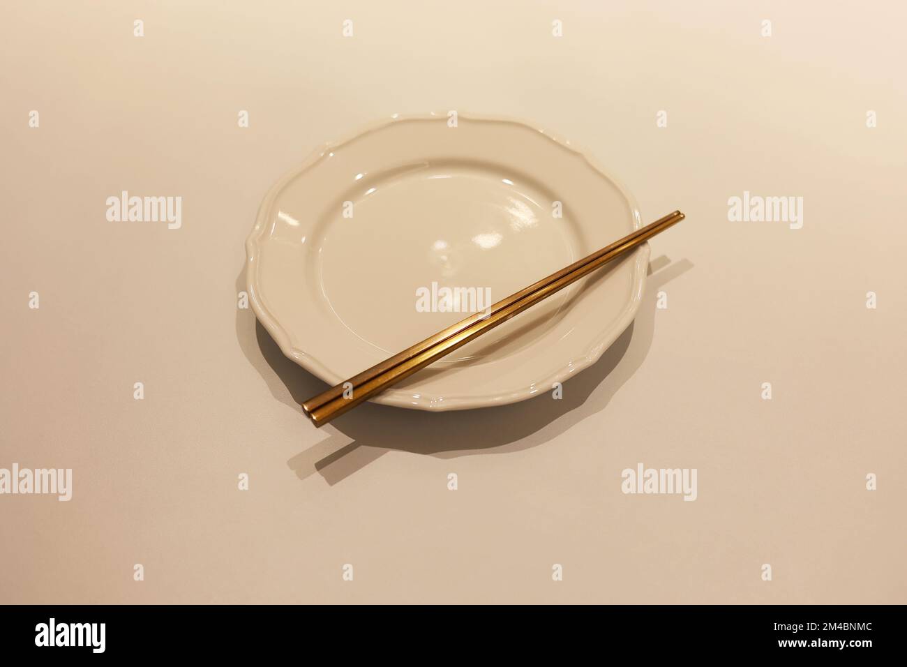 Ein Set koreanischer Messingstäbchen mit leerer weißer Schüssel auf dem Tisch, der Stäbchen auf der Schüssel Stockfoto
