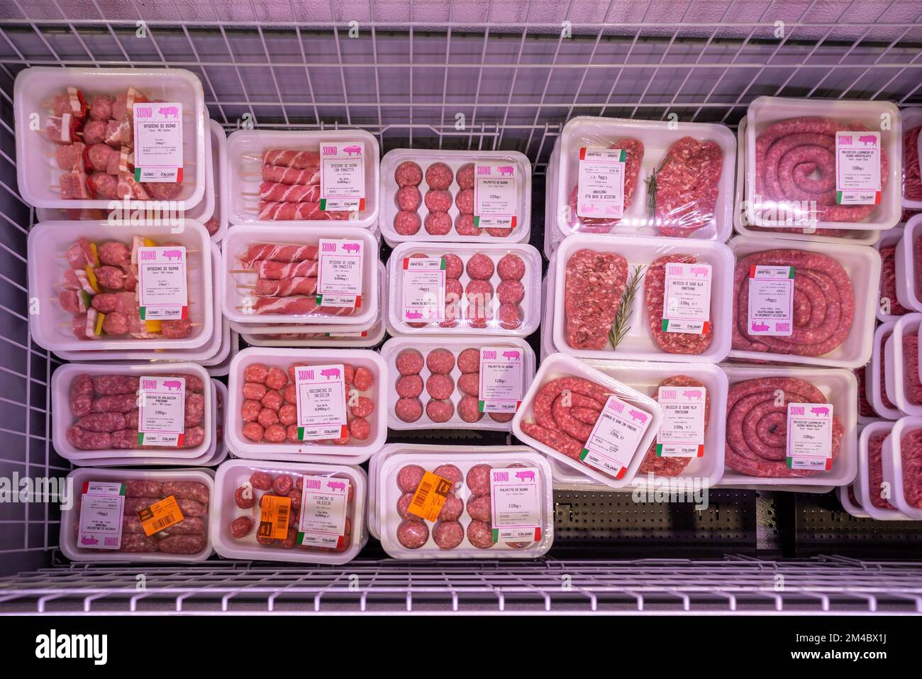 Rohes Schweinefleisch in Kühltheke zum Verkauf im italienischen Supermarkt, Wurst, Fleischklößchen und Kebabs in Tabletts aus Lebensmittelkunststoff mit Gewicht und Preisen labe Stockfoto