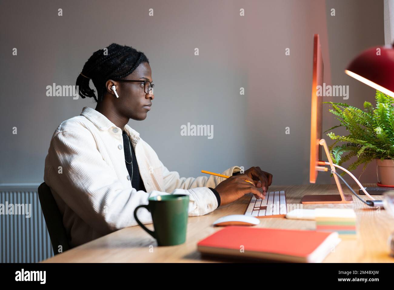 Fokussierter afrikanischer freiberuflicher Webentwickler, der Code schreibt, Computer benutzt, im Home Office sitzt Stockfoto