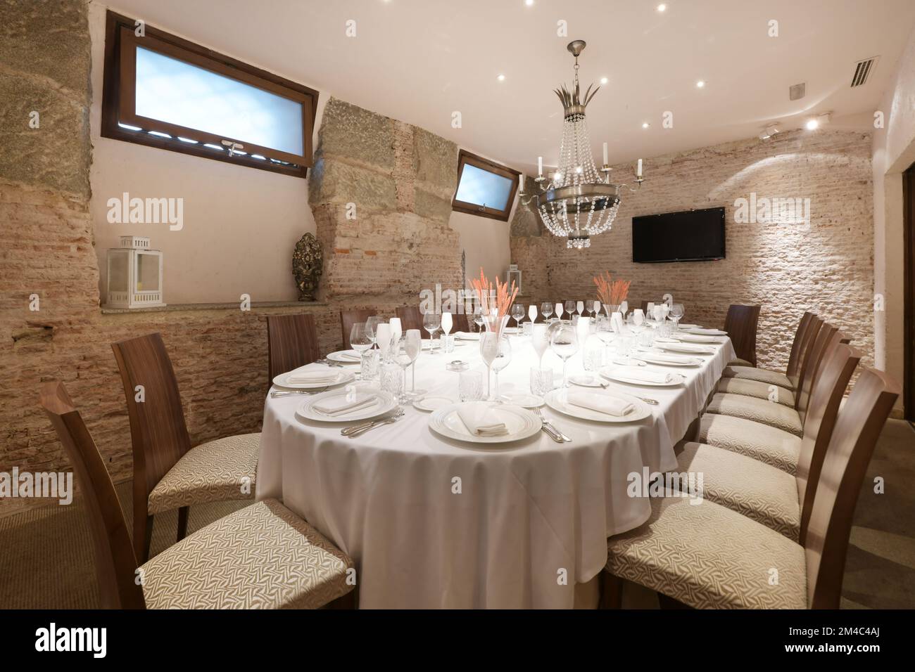 Esstisch eines Restaurants mit Service-Set mit Gläsern und Tellern und einer Zierlampe an der Decke Stockfoto
