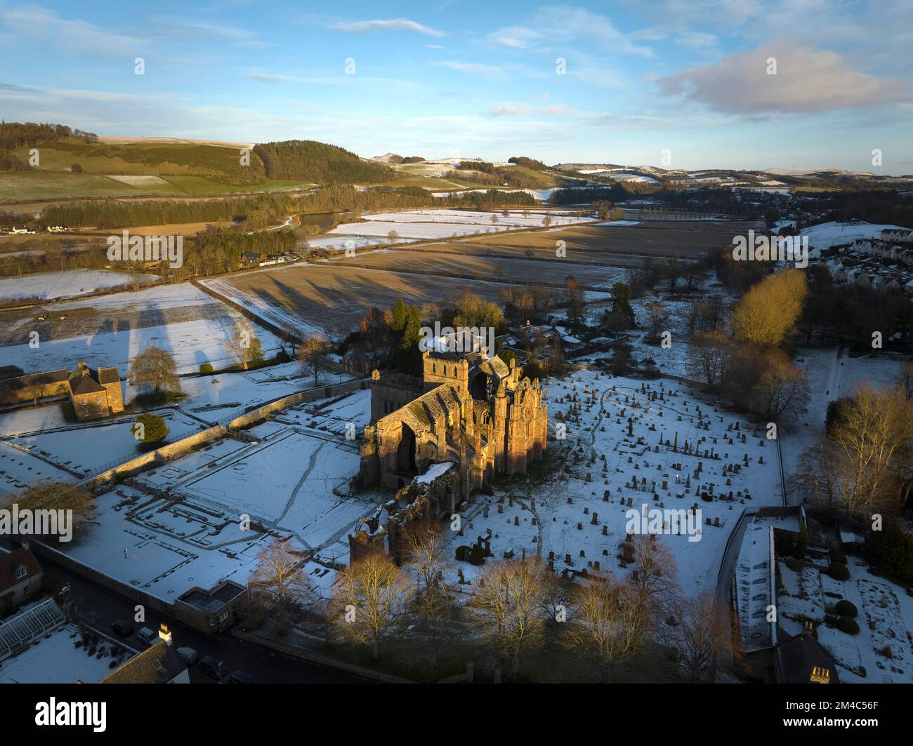 Luftaufnahme von Melrose Abbey und dem Haus des Commendators mit einer Schicht Schnee und Frost bei Sonnenuntergang an einem frischen Wintertag im Dezember. Stockfoto