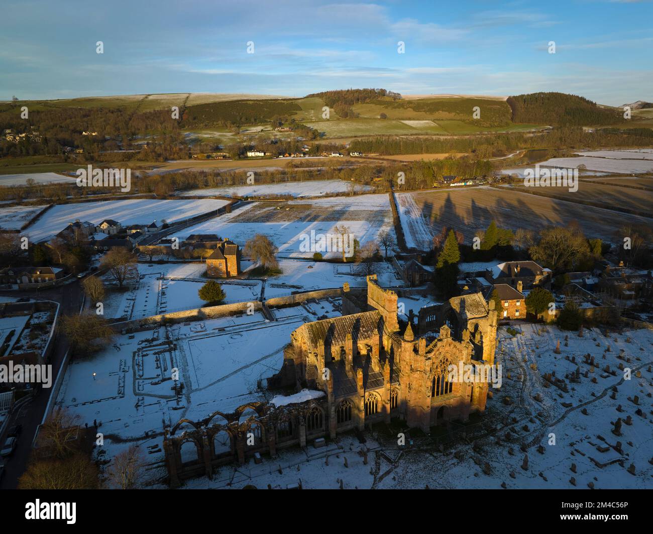 Luftaufnahme von Melrose Abbey und dem Haus des Commendators mit einer Schicht Schnee und Frost bei Sonnenuntergang an einem frischen Wintertag im Dezember. Stockfoto
