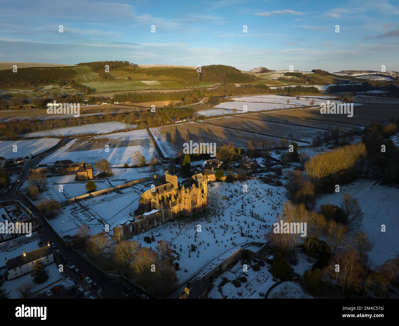 Luftaufnahme von Melrose Abbey und dem Haus des Commendators mit einer Schicht Schnee und Frost bei Sonnenuntergang an einem frischen Wintertag im Dezember. Stockfoto