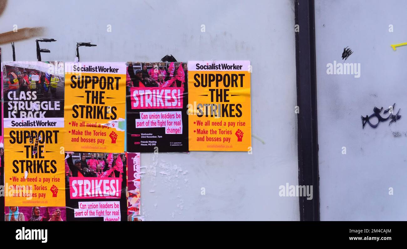 Auf den Plakaten auf der linken Seite, von denen einige von der Sozialdemokratischen Arbeiterin produziert wurden, heißt es, dass man die Streiks am Fenster eines leeren Ladens in Manchester, England, unterstützt. Krankenschwestern, Eisenbahn- und Postarbeiter streiken derzeit. Stockfoto