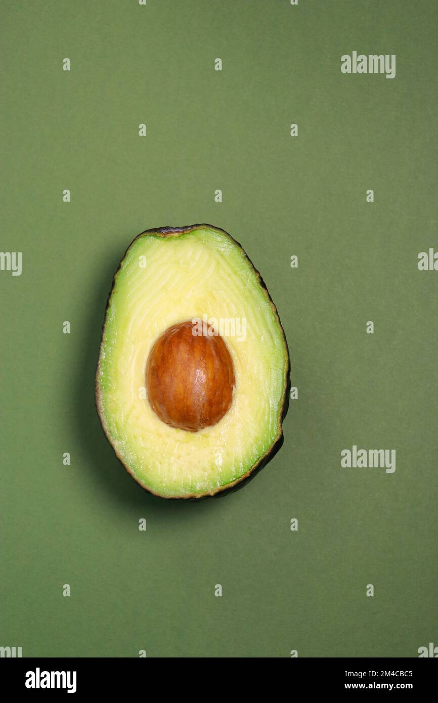 Nahaufnahme von frischer reifer Avocado auf grünem Hintergrund, Kopierbereich Stockfoto