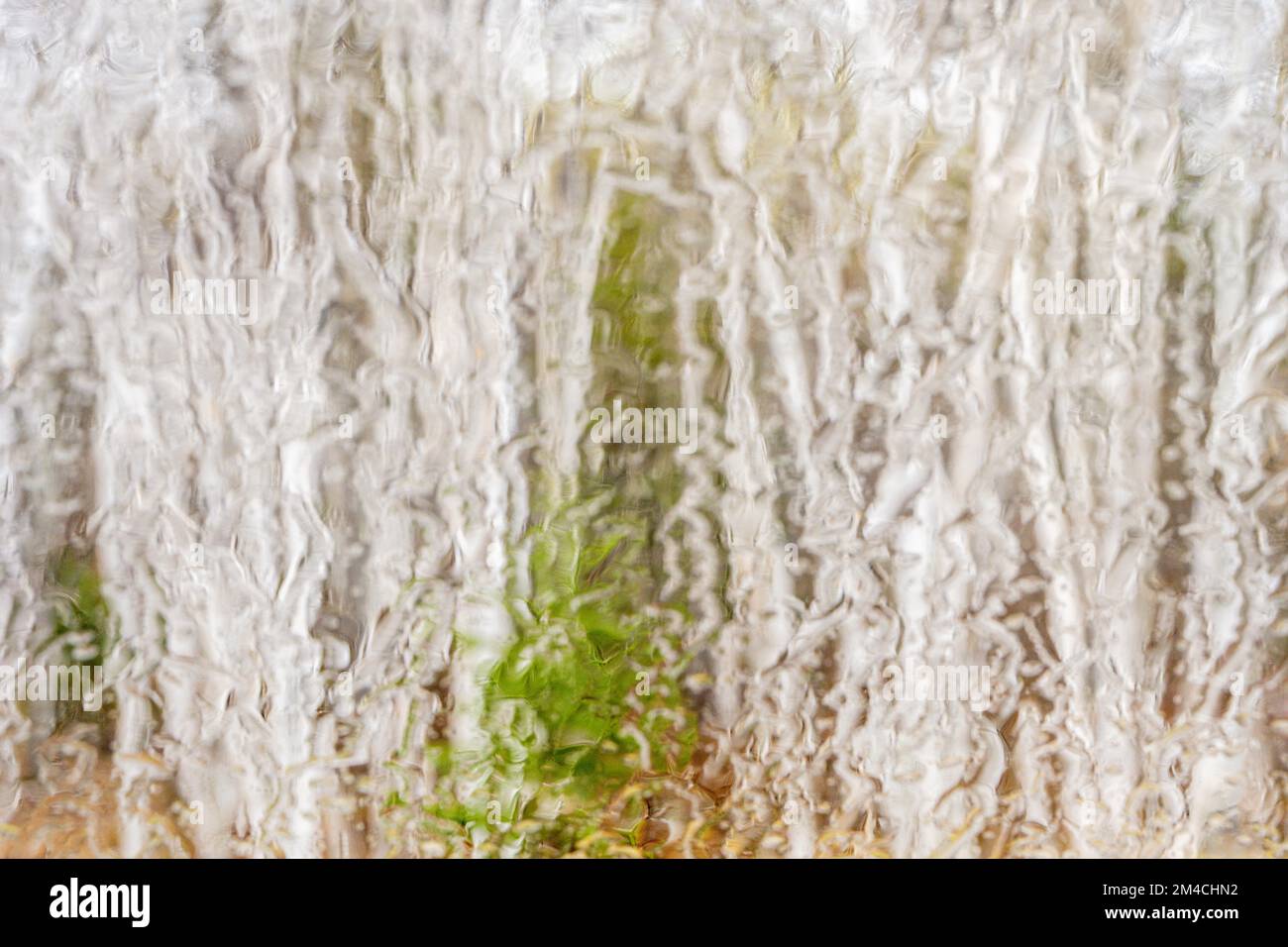 Waldgebiet im Frühling, das durch eine regenüberflutete Windschutzscheibe im Großraum Sudbury, Ontario, Kanada, zu sehen ist Stockfoto