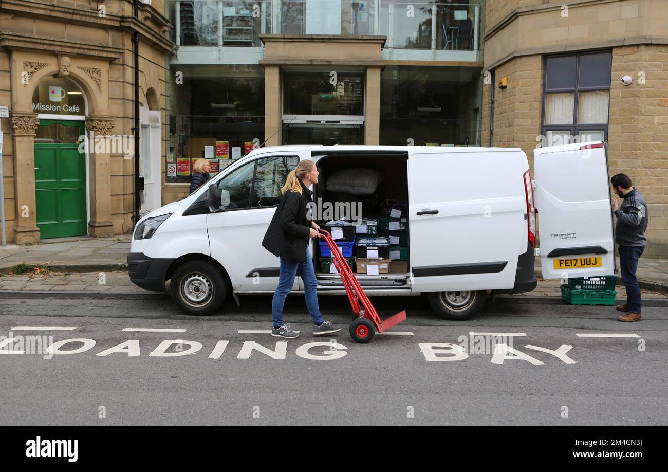 Die Freiwilligen Michelle und Paul laden einen Lieferwagen mit Lebensmittelpaketen zur Auslieferung vor das Welcome Center in Huddersfield in West Yorkshire. Die Welcom Stockfoto