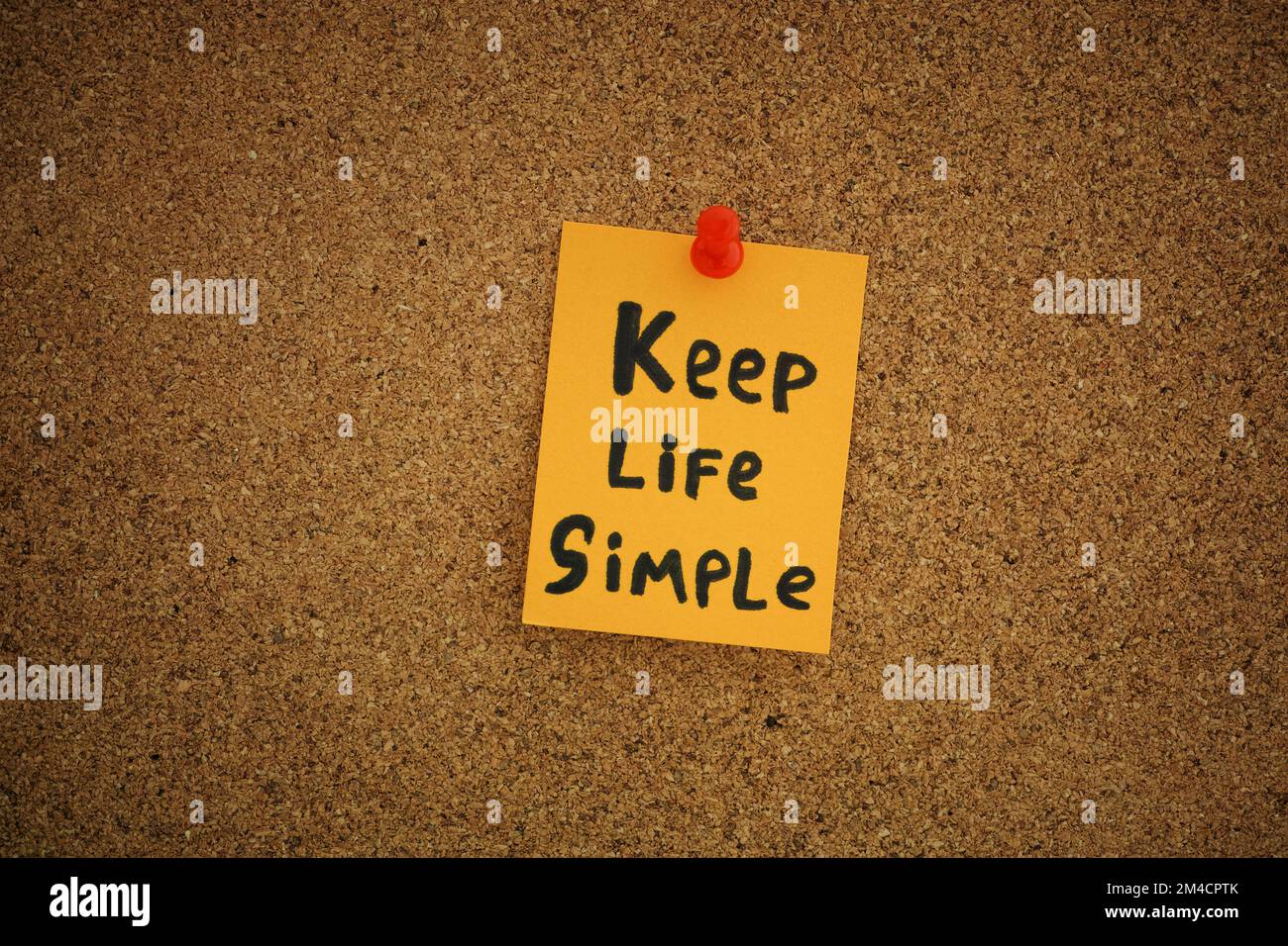 Ein gelber Zettel mit den Worten "Keep Life Simple", an einer Korktafel befestigt. Schließen. Stockfoto